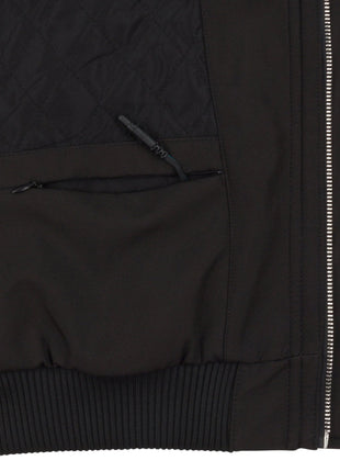 Close up of the interior jacket area on wearer's left side at the lower corner near the zipper. The battery storage pocket can be seen zipped open with the heating system connector wire protruding from the jacket, demonstrating where the small battery pack is stored. Interior quilted lining can be seen.